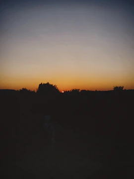 A vibrant sunset behind a silhouette of a person reciting poetry outdoors.