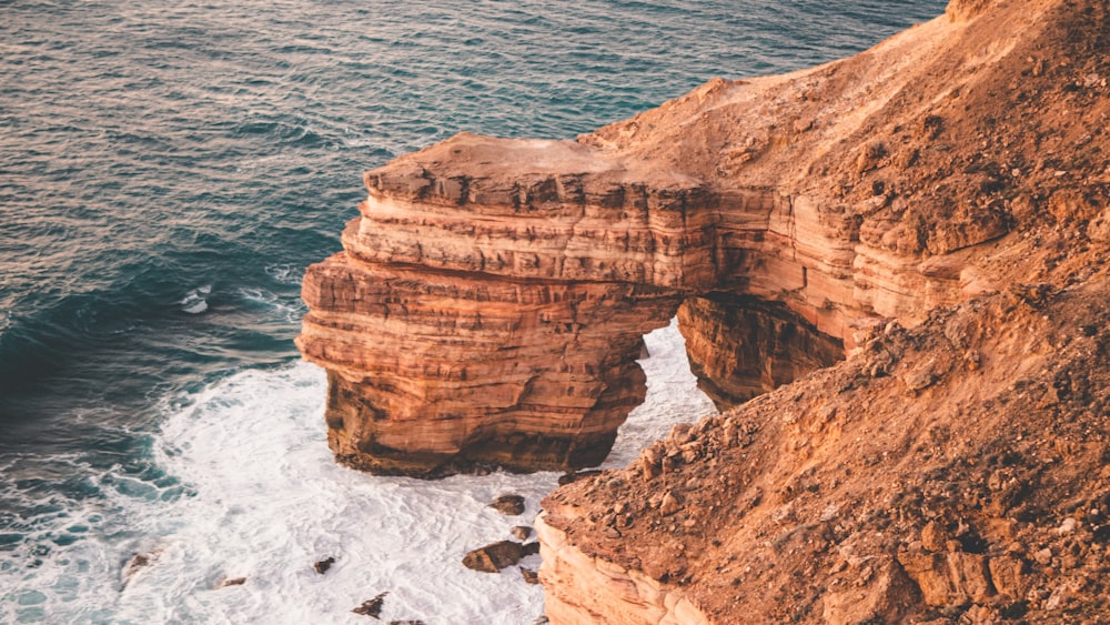 brown rock formation near body of water during daytime