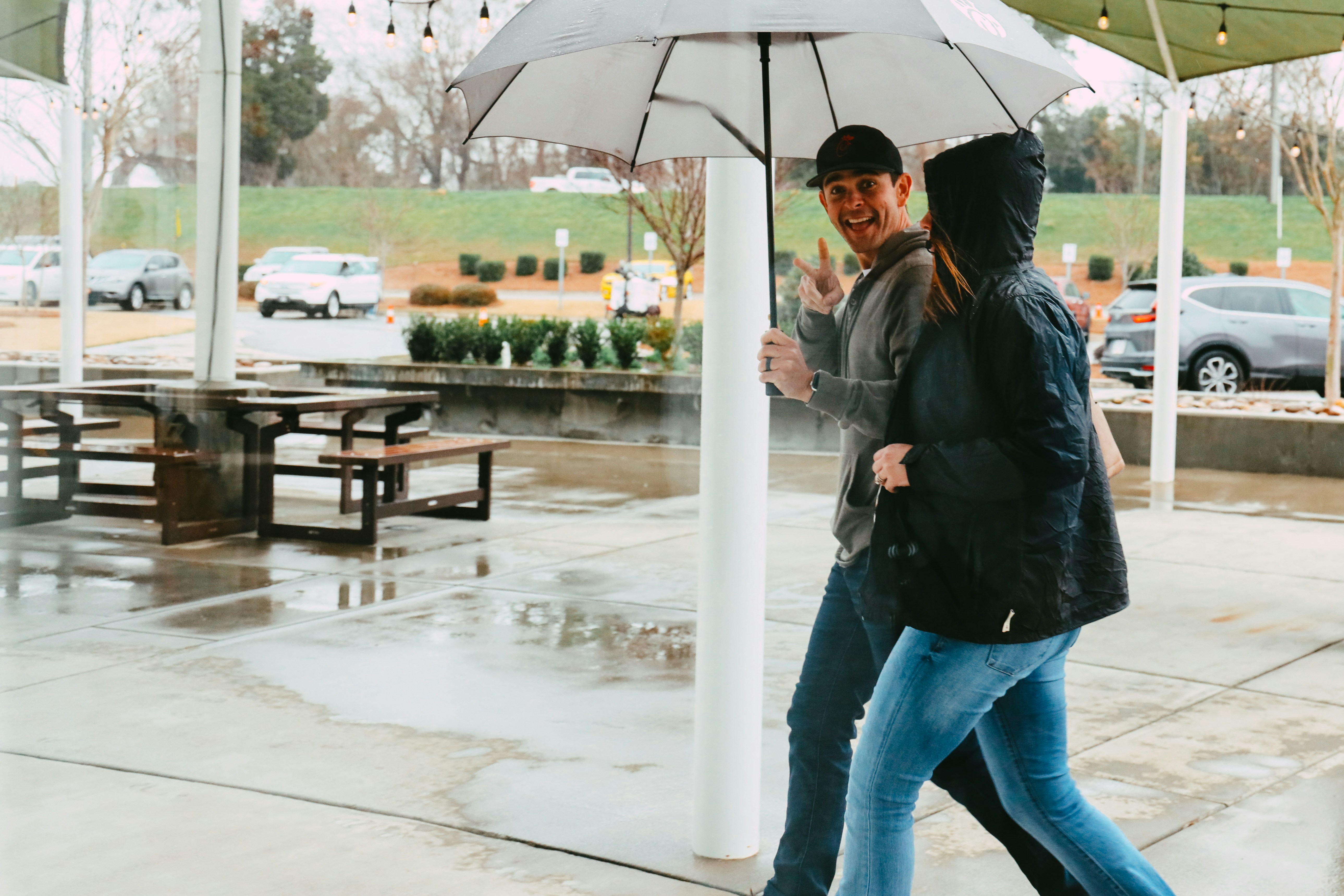 woman in black jacket and blue denim jeans holding umbrella