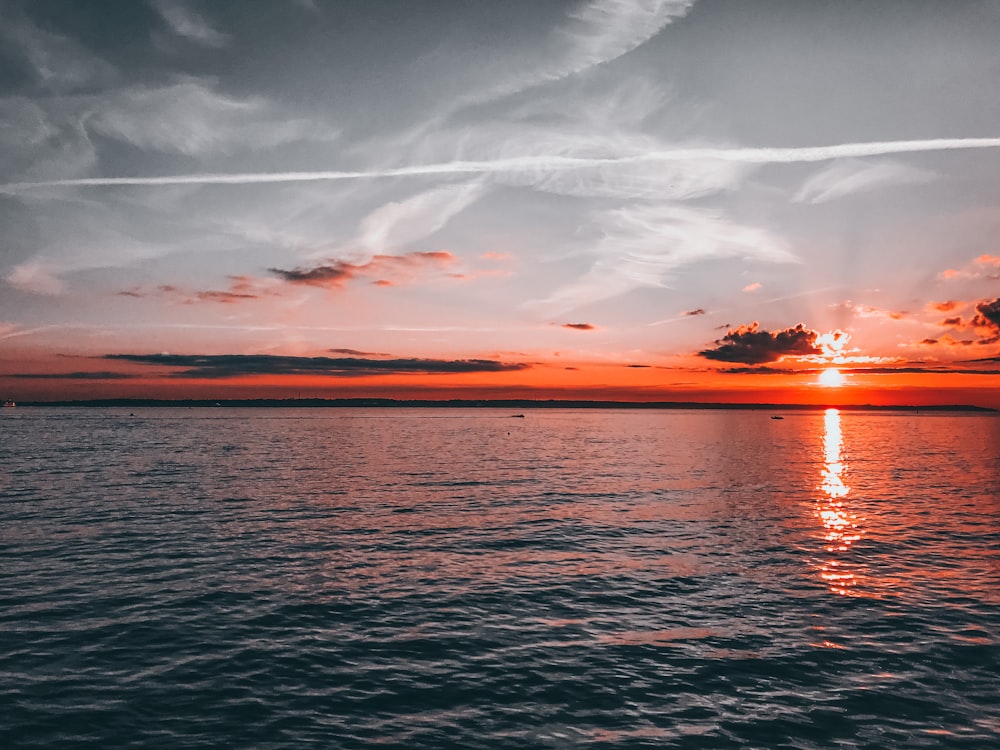 Cuerpo de agua bajo cielo nublado durante la puesta del sol