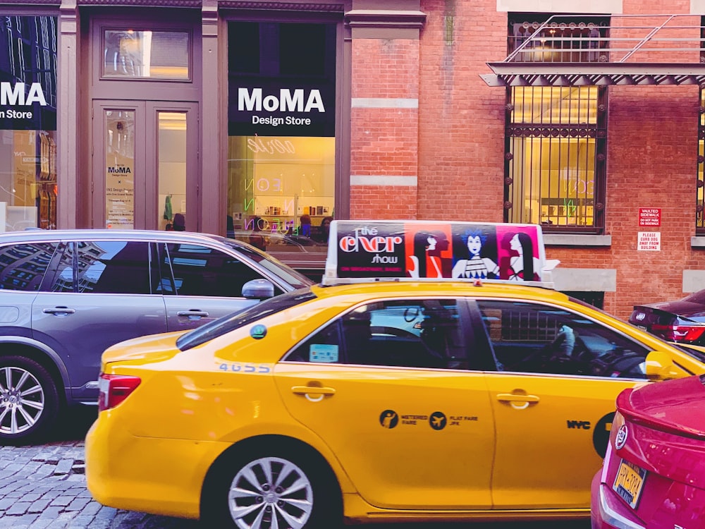 yellow taxi cab parked beside brown brick building during daytime