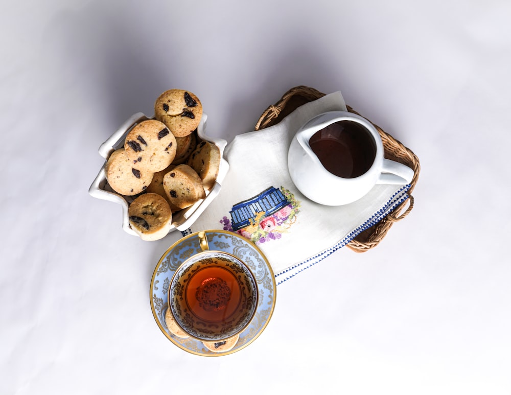 white ceramic mug with coffee beside cookies on white ceramic saucer