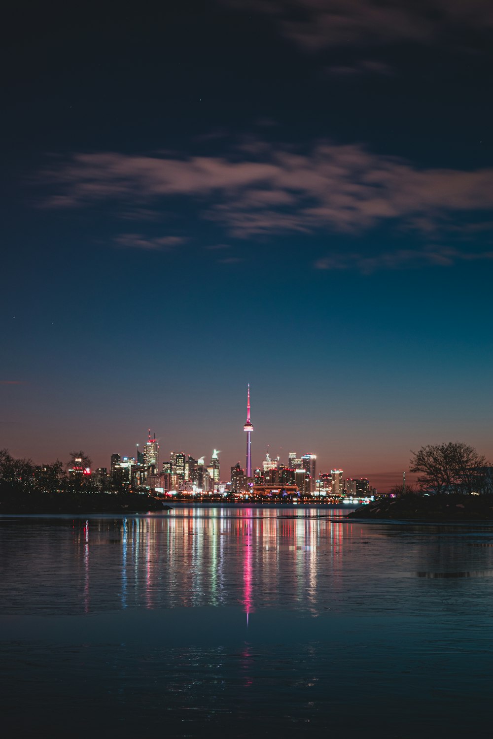 city skyline across body of water during night time