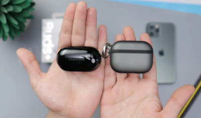 black samsung bluetooth earbuds on persons hand