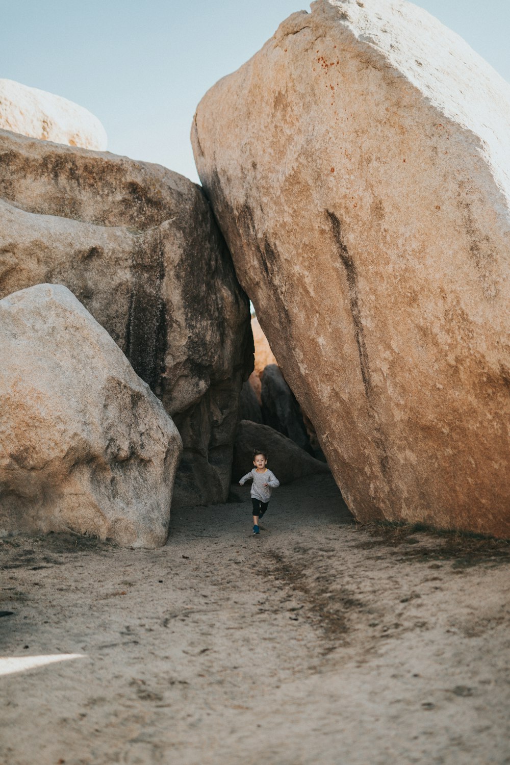 woman in white shirt and black pants standing beside brown rock formation during daytime