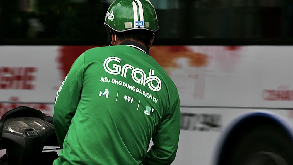 赤いヘルメットをかぶった緑と白のUNK UNK長袖シャツを着た男性