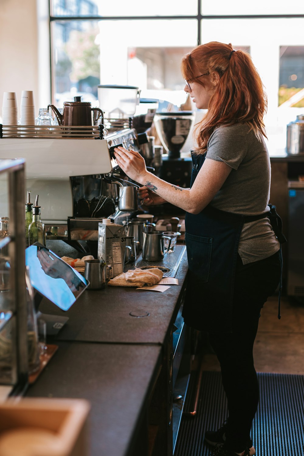woman in gray t-shirt pouring coffee on coffee machine