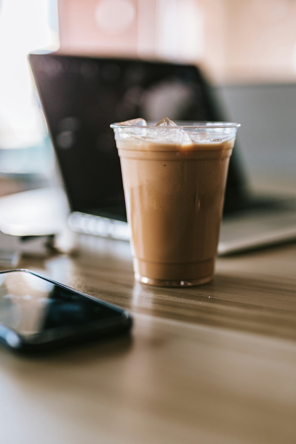 black iphone 5 beside clear drinking glass with brown liquid