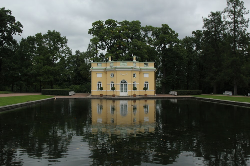 Edificio in calcestruzzo giallo vicino agli alberi verdi e al fiume durante il giorno