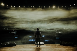 man in black suit standing on stage