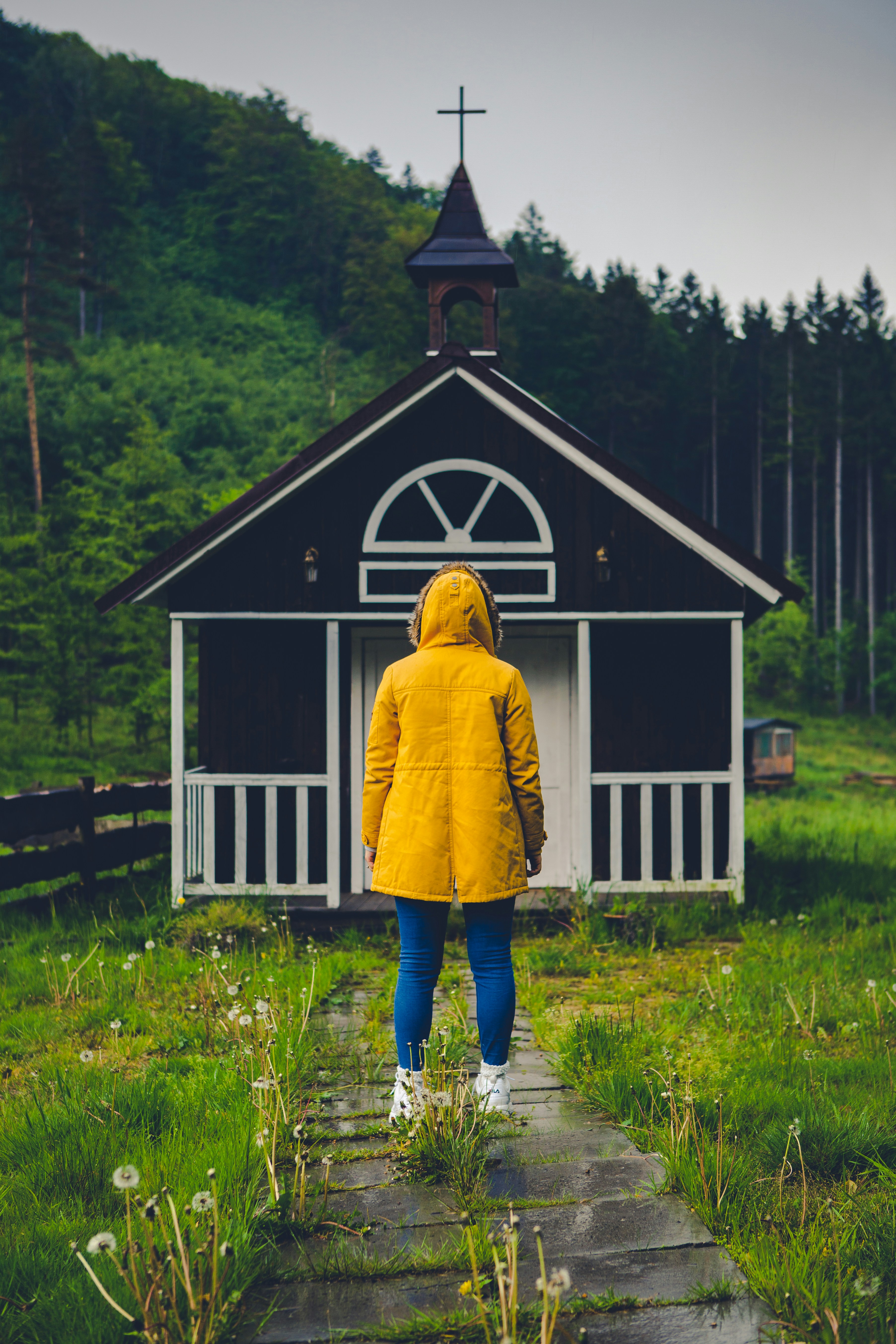 person in yellow coat standing in front of white wooden house