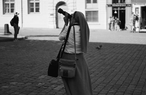Portrait of Somayah Elhassawy holding a camera in an urban street setting.