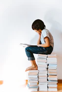 woman in gray t-shirt and blue denim jeans reading book