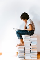 woman in gray t-shirt and blue denim jeans reading book