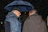 Man wearing a dark blue waterproof jacket standing in a rainy urban street
