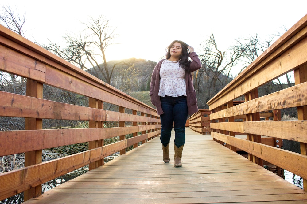 woman in blue denim jacket standing on wooden bridge during daytime