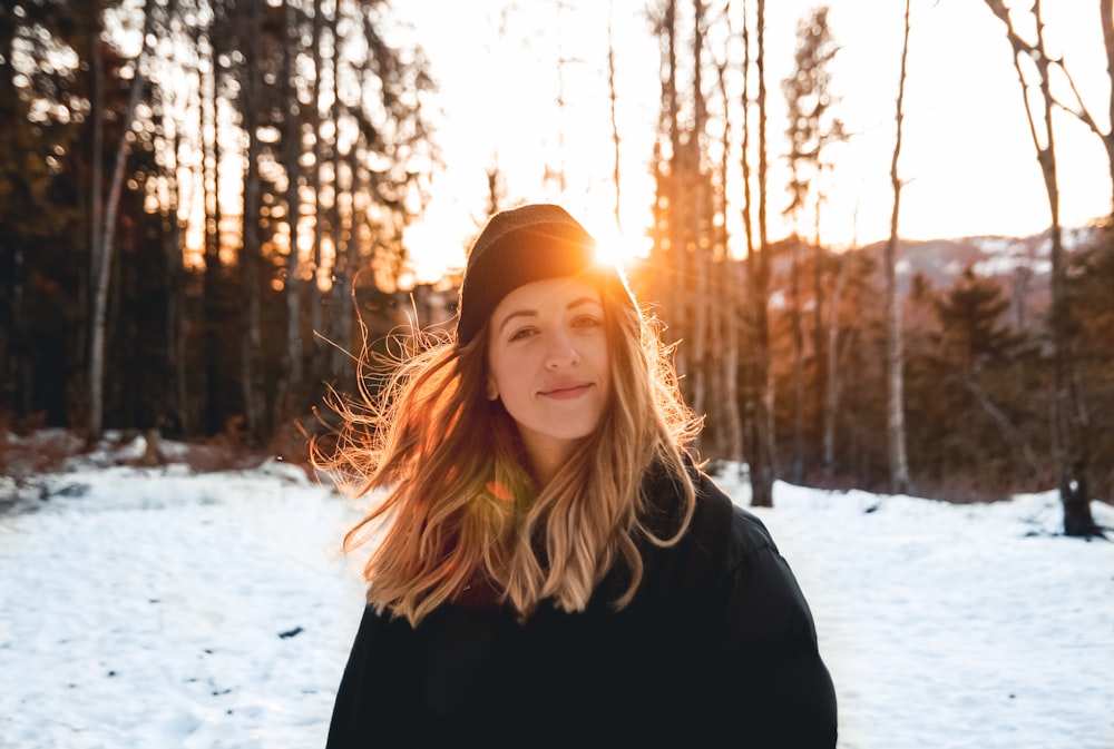 woman in black jacket and knit cap standing on snow covered ground during daytime