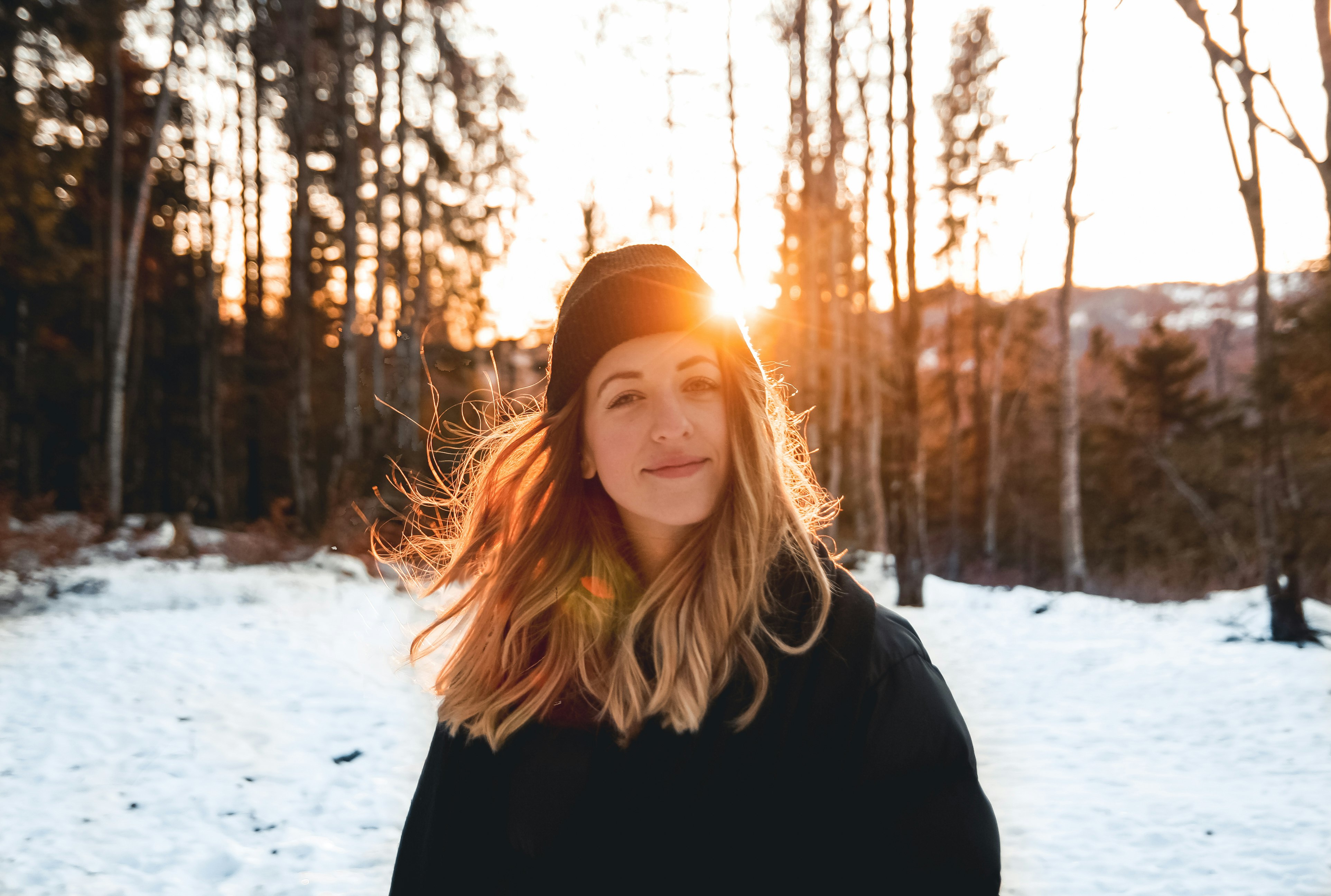 woman in black jacket and knit cap standing on snow covered ground during daytime