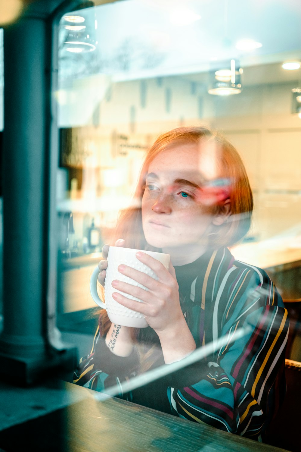 woman in blue and white striped shirt drinking from white ceramic mug