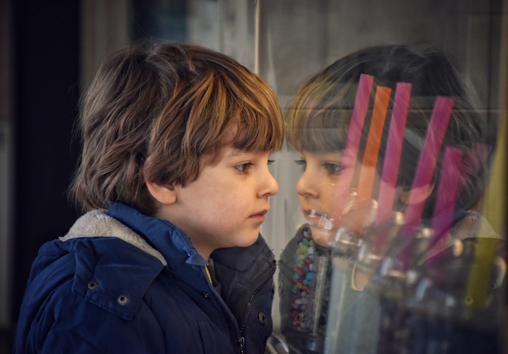 boy in black jacket looking at the glass window