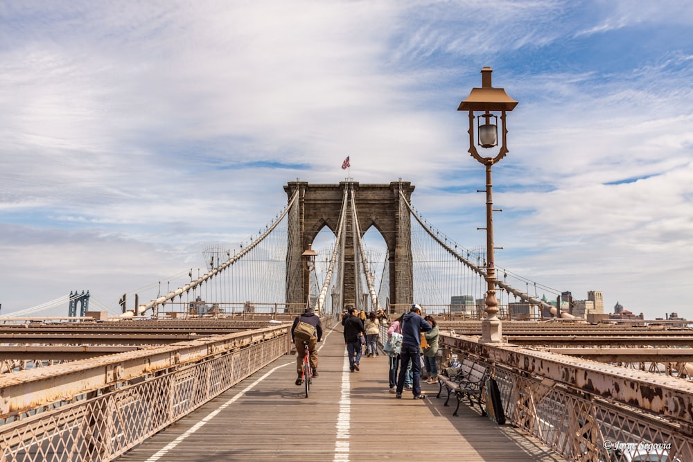 people walking on bridge under cloudy sky during daytime