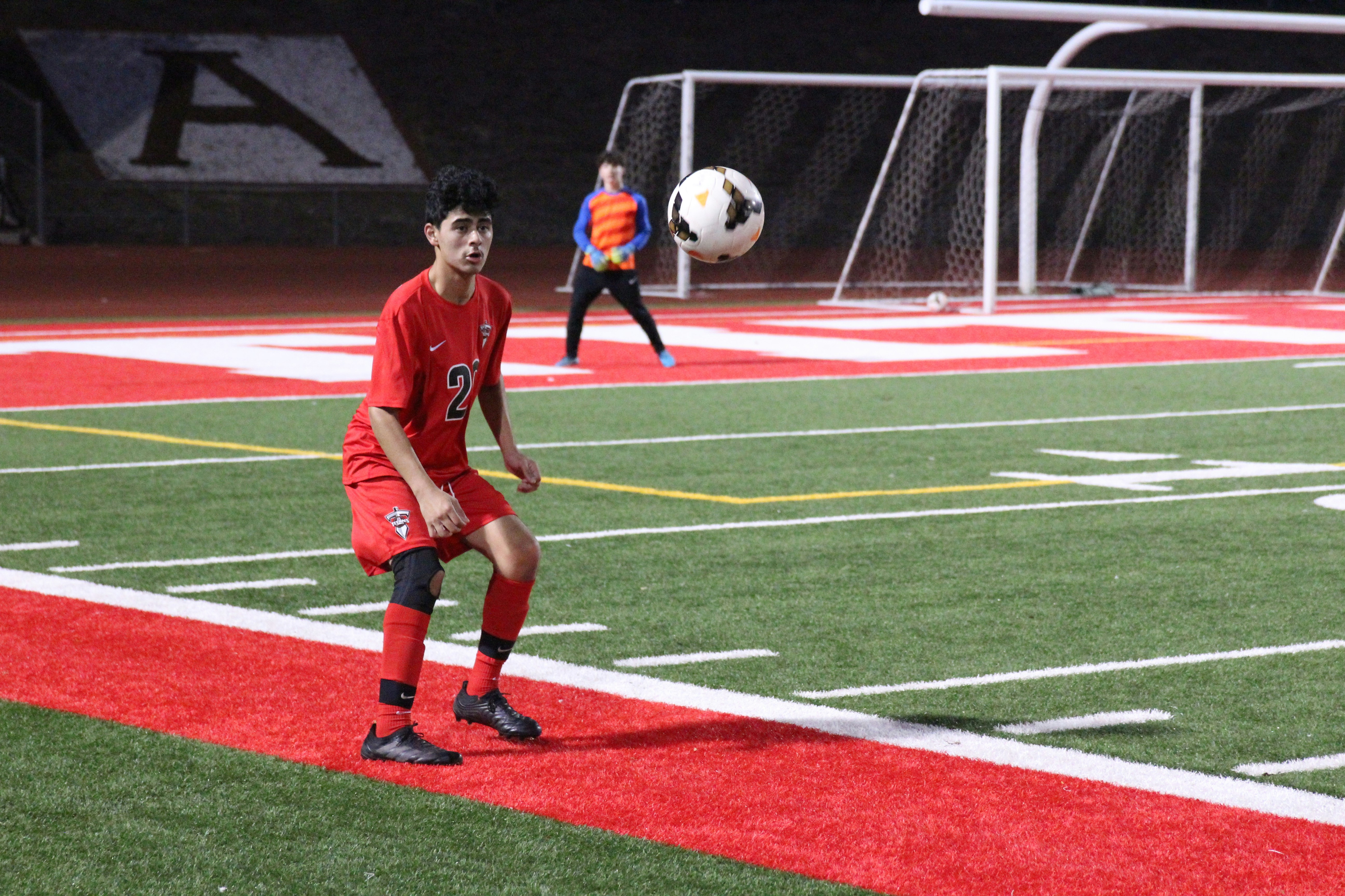 man in red soccer jersey kicking soccer ball