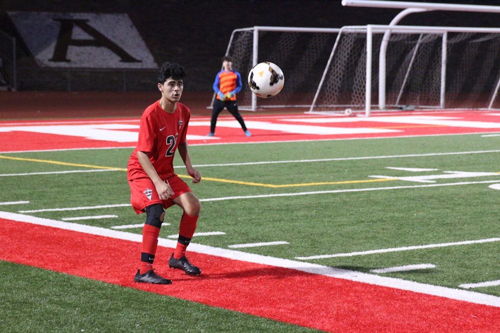 man in red soccer jersey kicking soccer ball