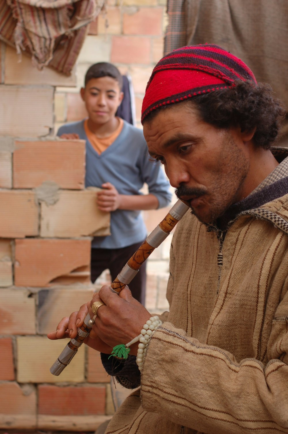 man in red knit cap holding brown wooden flute