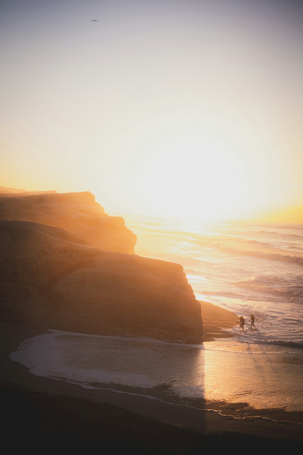 silhouette of person standing on seashore during sunset