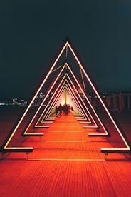 man in black jacket walking on brown wooden pathway during night time
