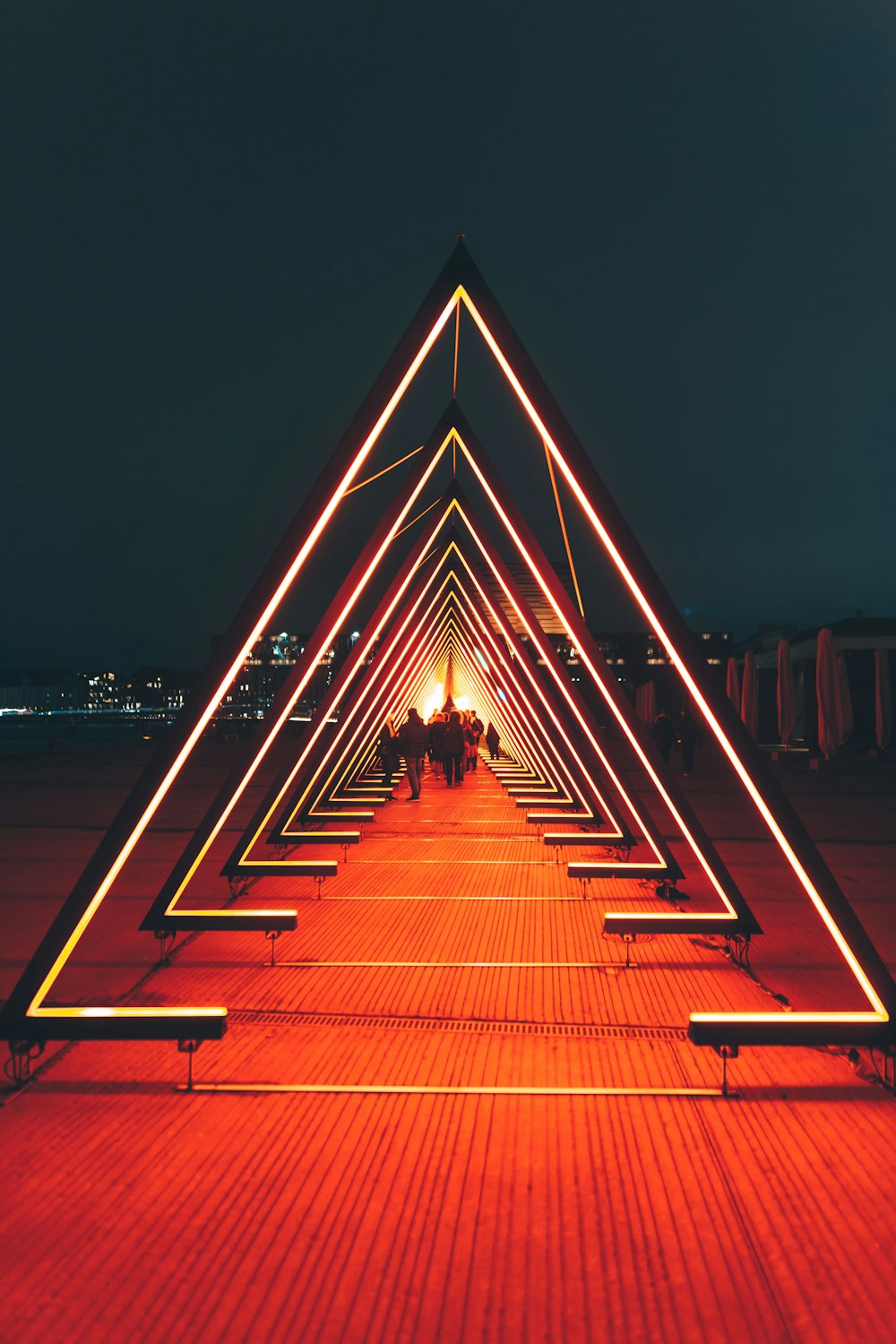 man in black jacket walking on brown wooden pathway during night time