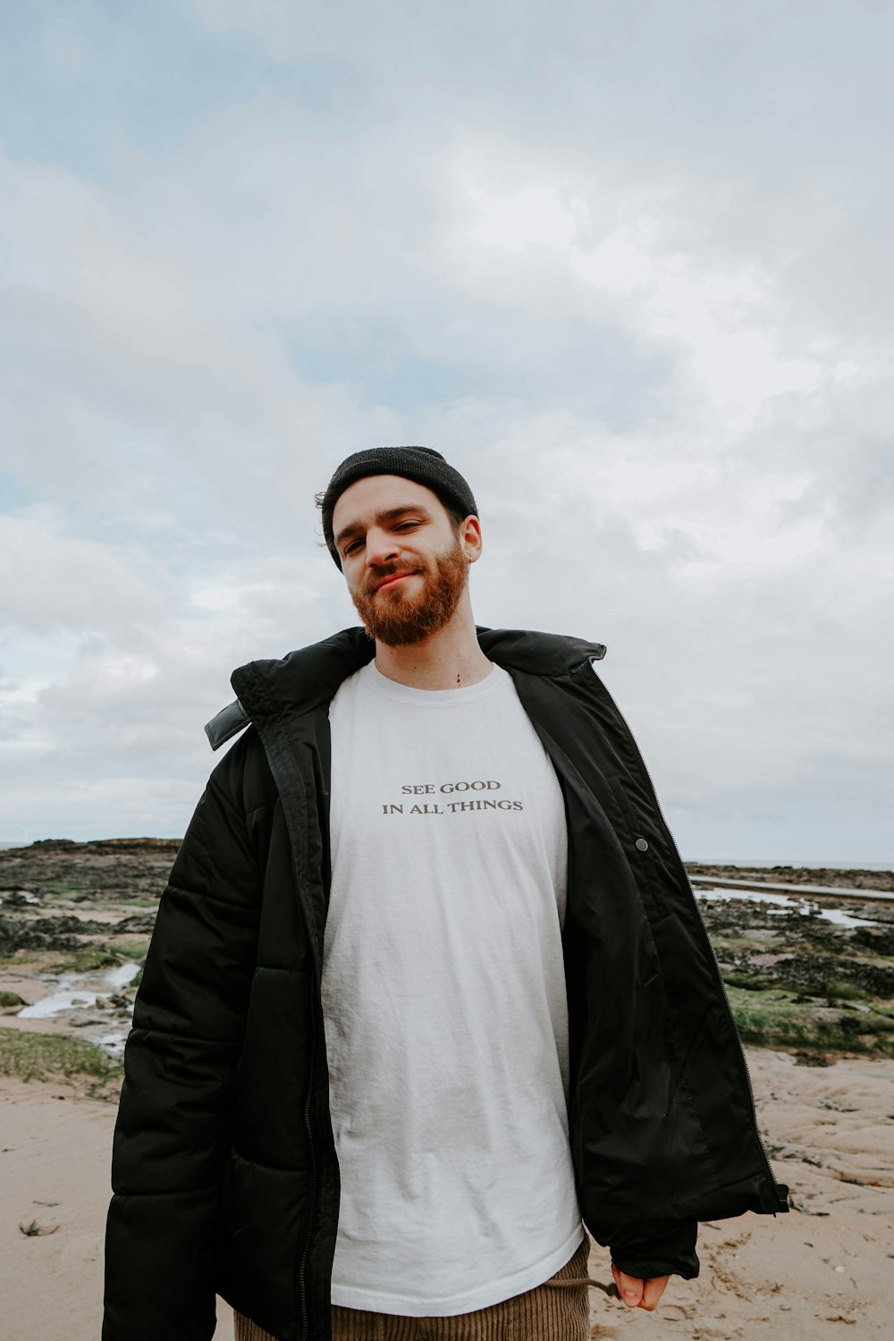 man in black jacket standing on beach during daytime