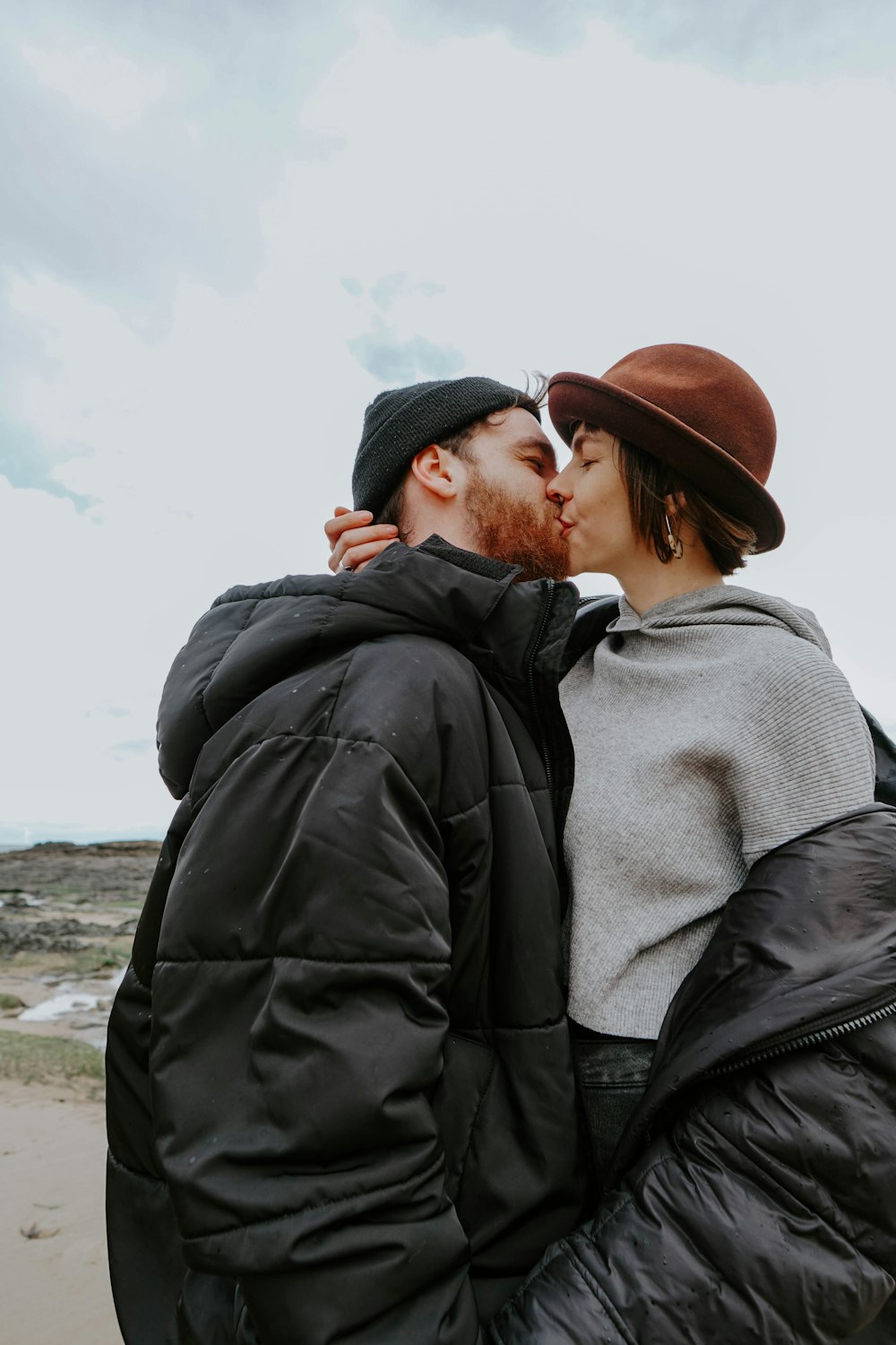 man in black jacket kissing woman in gray jacket