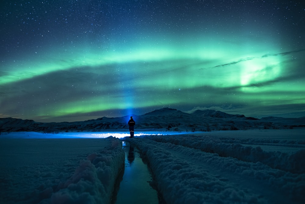 Persona in piedi su un terreno coperto di neve sotto il cielo verde
