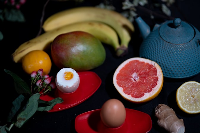 green apple fruit beside red round fruit on red ceramic plate