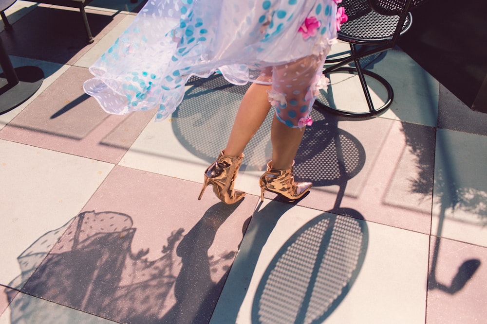 woman in white pink and green floral skirt and brown sandals