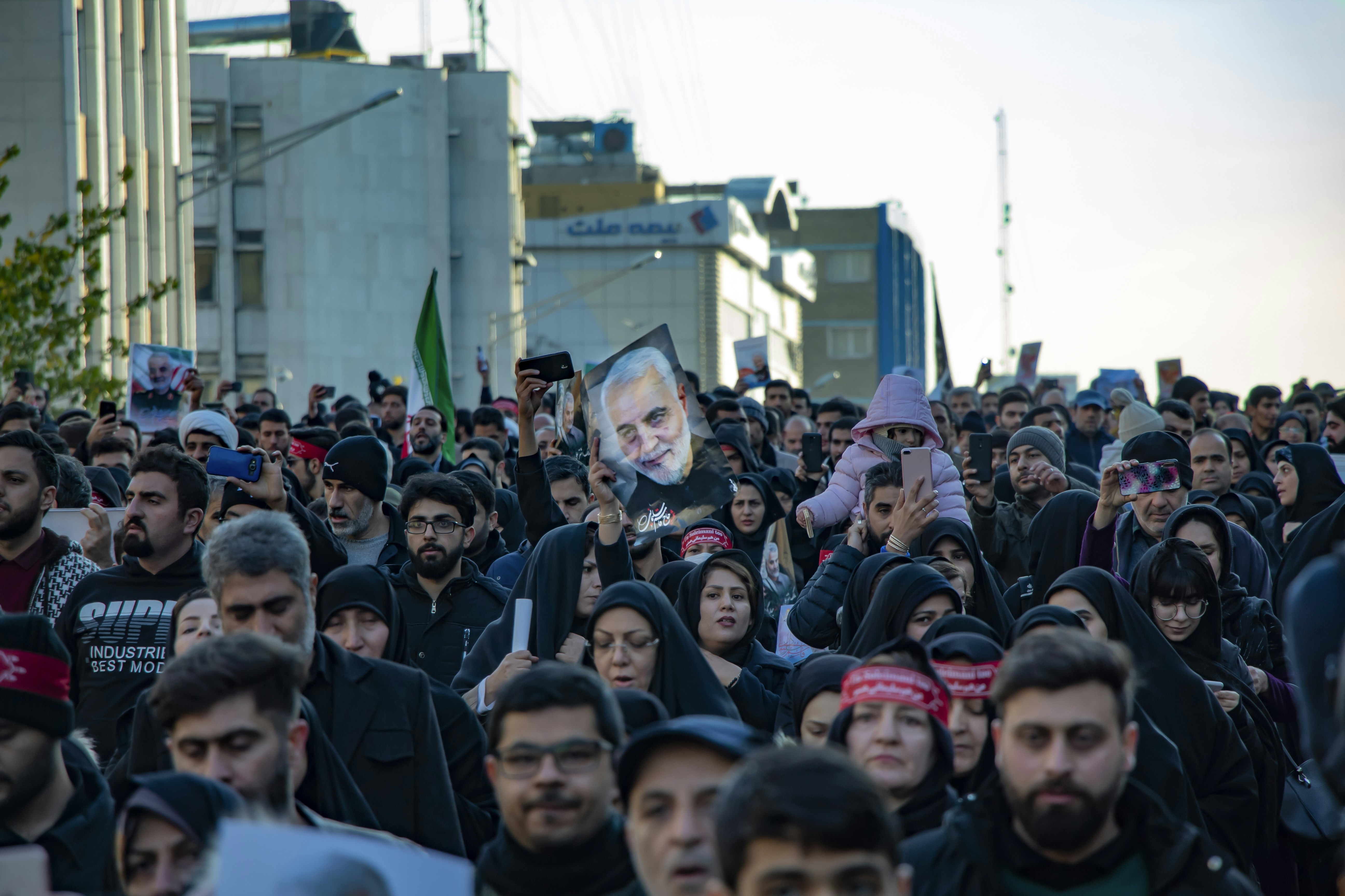 A poster of Qassem Soleimani held by crowd, during his funeral in Tehran, Iran. Photo by Mohammad Hosein Afshari. یک پوستر از شهید قاسم سلیمانی که توسط جمعیت بالا نگه داشته شده، در طی مراسم تشییع پیکر او در تهران، ایران. عکس از محمدحسین افشاری