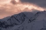 A dramatic landscape shot of mountains under a cloudy sky at dusk.