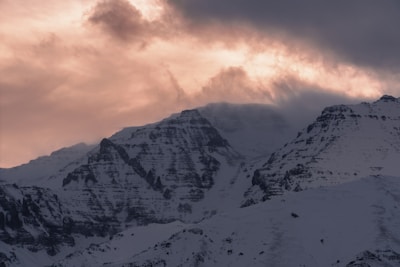 A dramatic landscape shot of mountains under a cloudy sky at dusk.