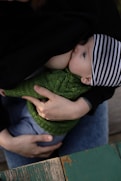 baby in black and white striped long sleeve shirt lying on green textile