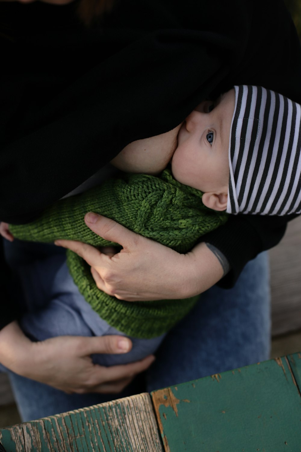 Baby in schwarz-weiß gestreiftem Langarmshirt auf grünem Textil liegend