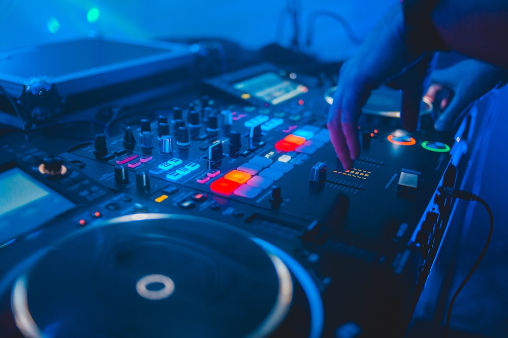 person playing dj mixer with blue lights