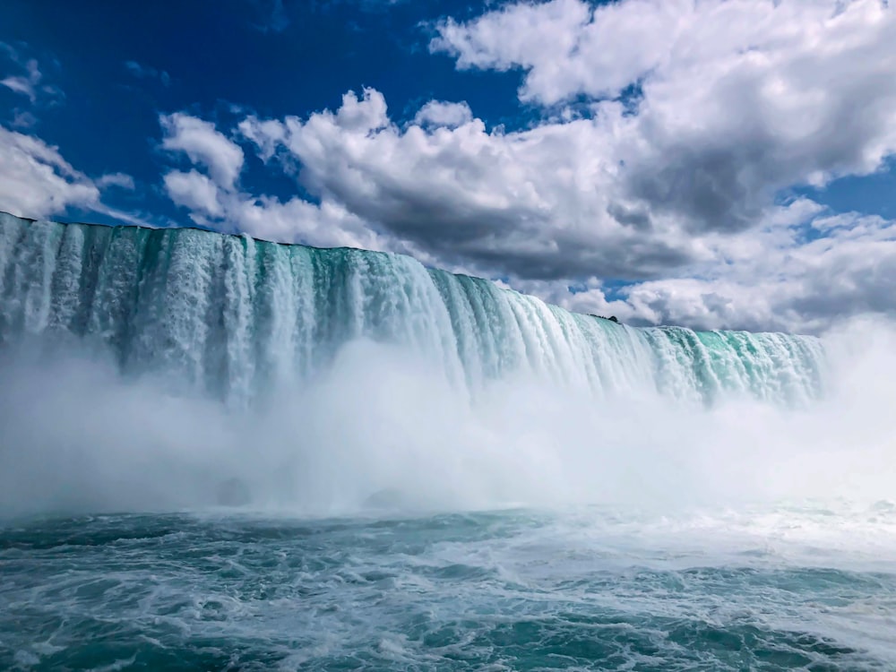 waterfalls under blue and white cloudy sky during daytime