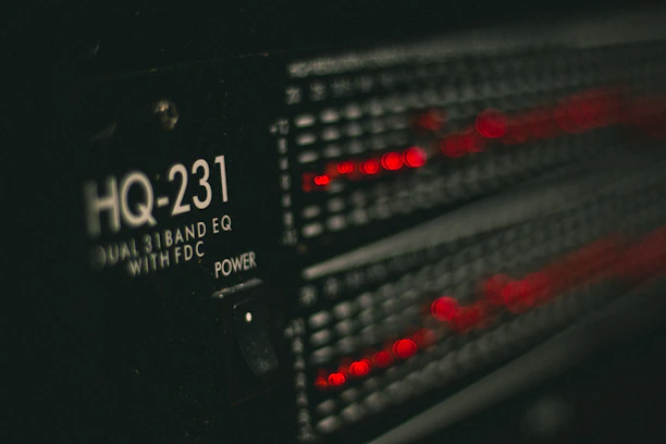 A close-up of a ham radio transceiver glowing softly under green and amber lights.