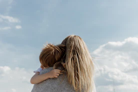 woman holding child from behind against cloudy sky