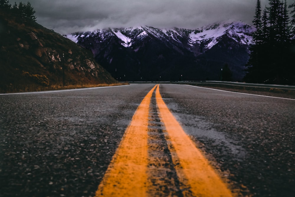 gray concrete road near snow covered mountain during daytime