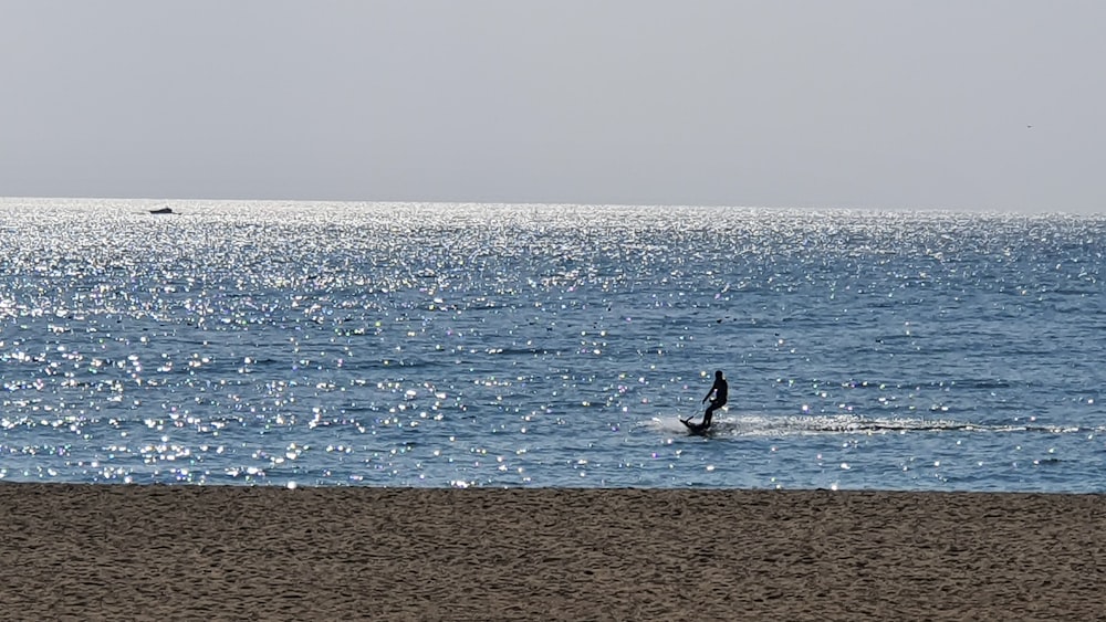 person in black shirt and black pants walking on beach during daytime