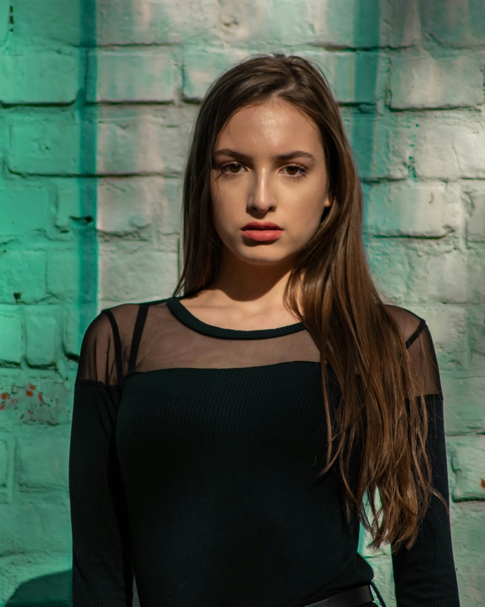 woman in black tank top standing beside blue wall