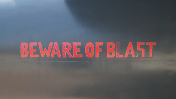 A stark red warning sign with bold text 'Beware Greg Secker Schemes' against a clean white background.