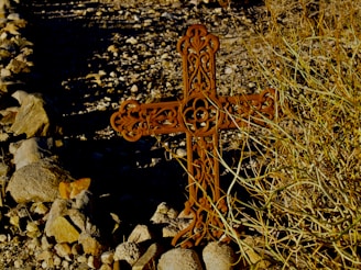 A man carrying a cross in a dry landscape.